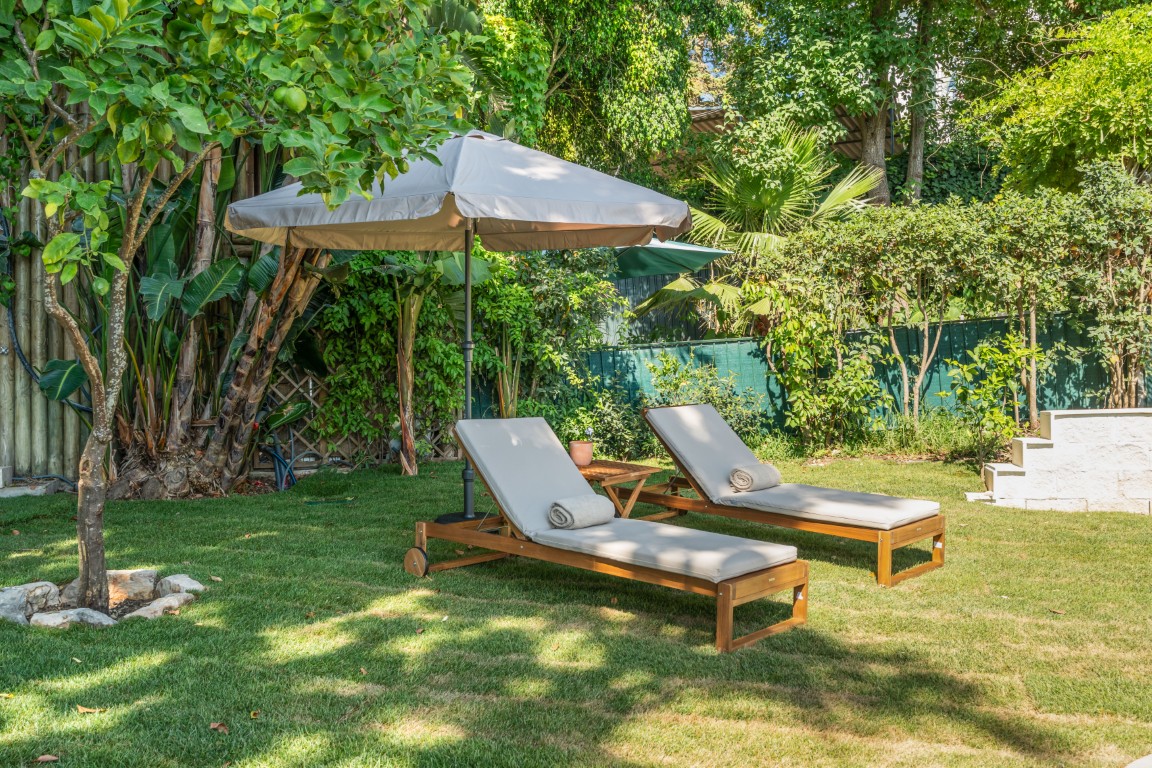 Espreguiçadeiras no jardim, à sombra das árvores